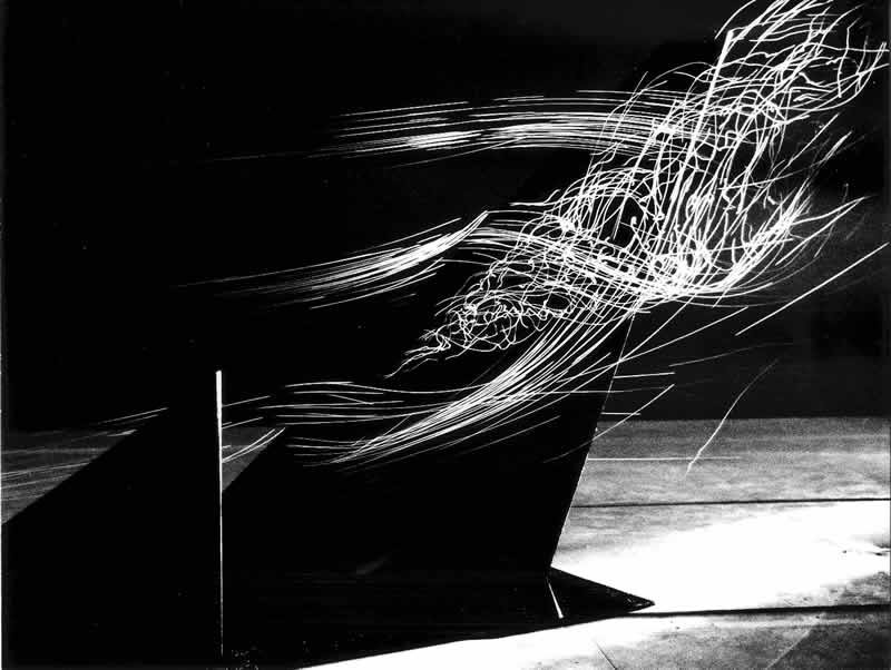 Helium bubble streaklines over a canard wing model in a wind tunnel, showing flow separation and vortex structure against a black background.